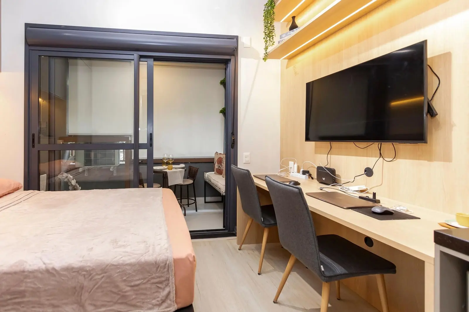 Ambiente integrado do Studio Ipê com bancada de trabalho, TV e sacada envidraçada