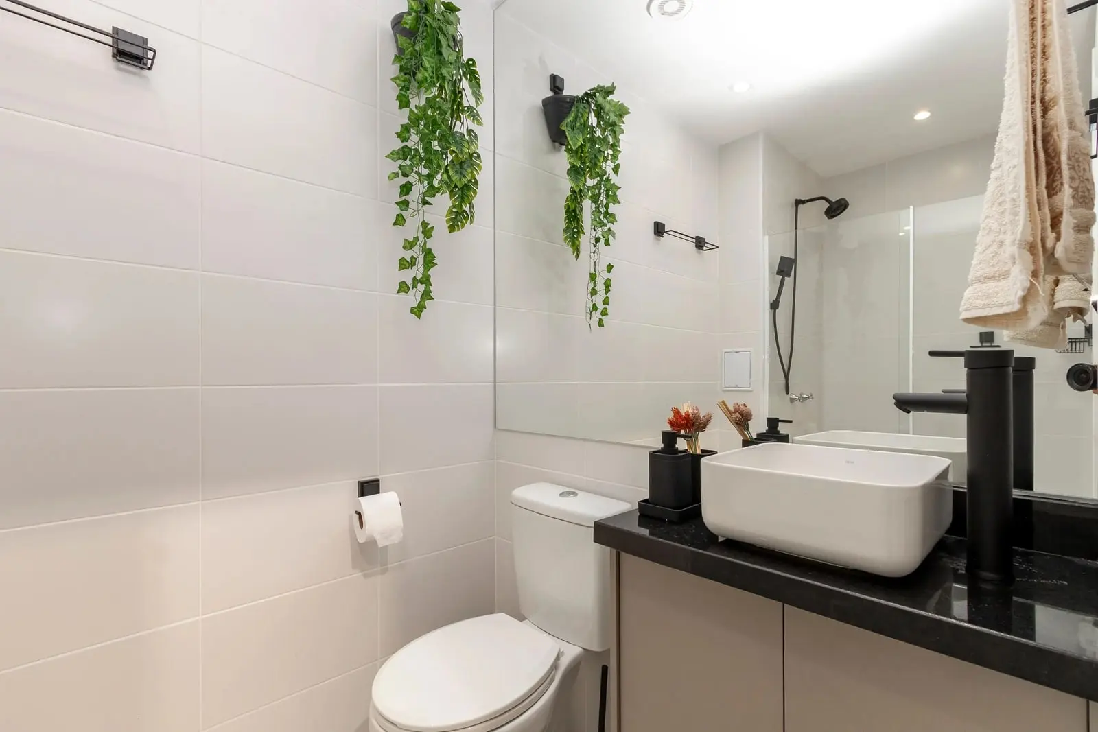 Banheiro do Studio Ipê com bancada, vaso sanitário e plantas pendentes