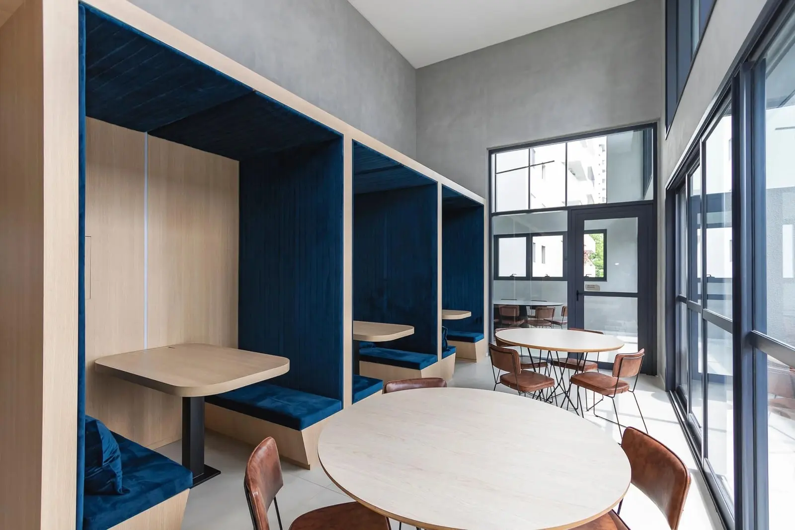 Espaço de coworking do Haus Mitre Campo Belo com baias de estofado azul e mesas de madeira